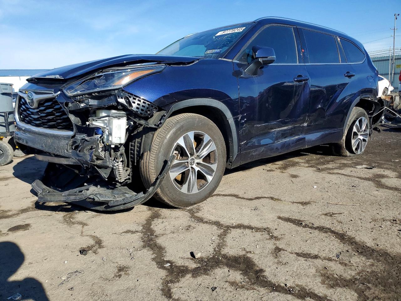 A silver 2020 Toyota Highlander XLE SUV with deployed orange airbags visible through the windshield and front-end damage at a tow yard